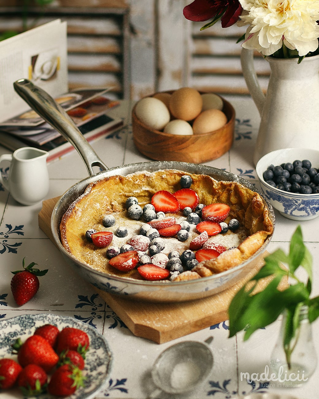 Clatita Dutch Baby dulce, cu zahar pudra, capsuni si afine deasupra