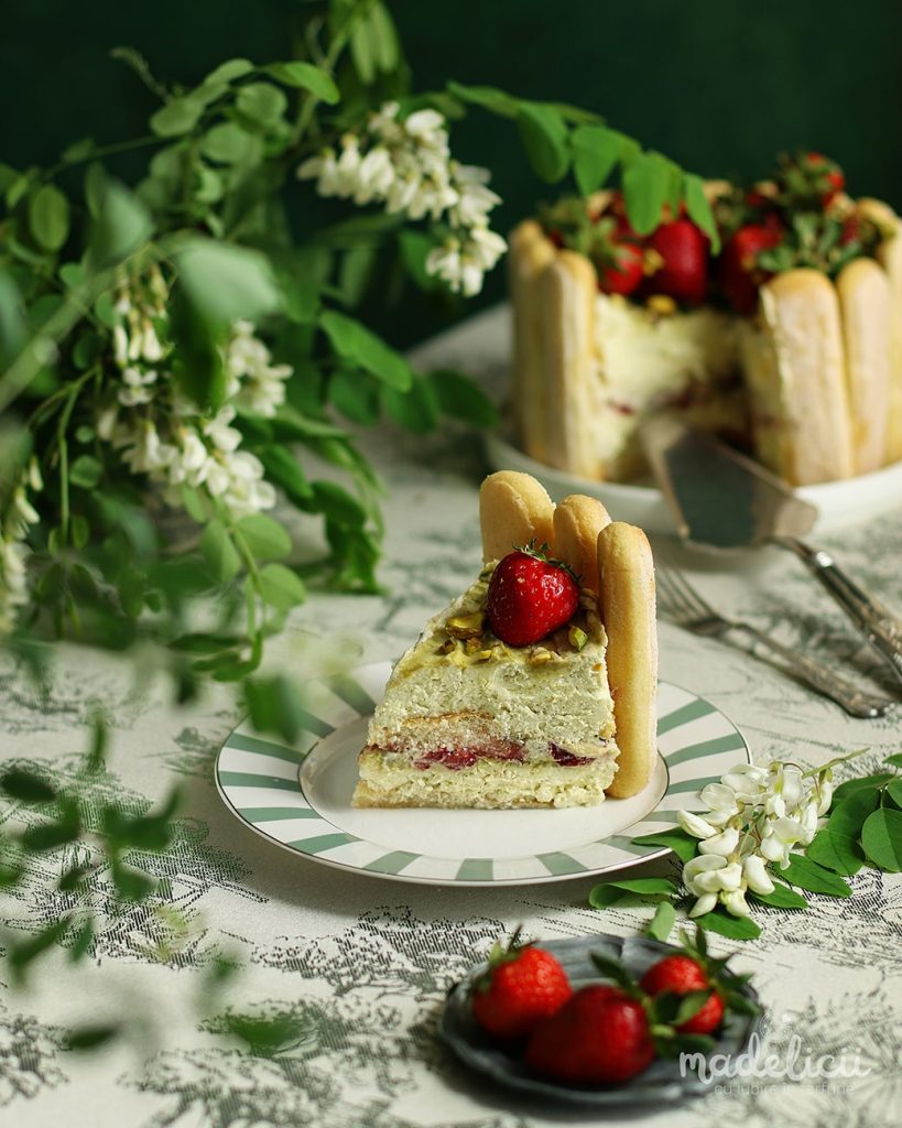 Felie de tort tiramisu cu fistic si capsuni pe farfurie, desert racoritor de vara cu crema de mascarpone si piscoturi insiropate.
