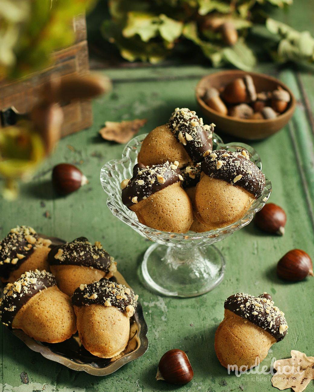 Briose in forma de ghinda glazurate cu ciocolata si alune de padure, servite pe un platou elegant